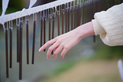 A closeup shot of a woman's hand touching brown wind chimes