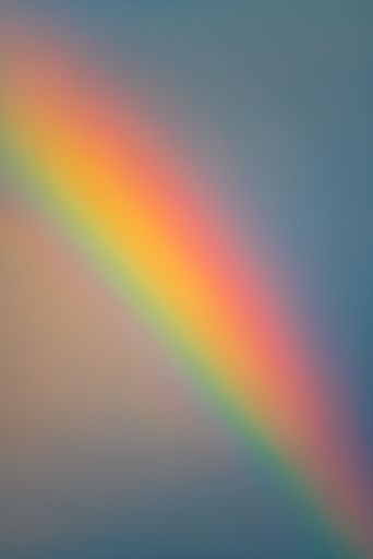 A vertical shot of a bright rainbow with blue sky in the background