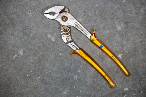 A closeup shot of a pipe wrench with shallow depth of field on a concrete floor