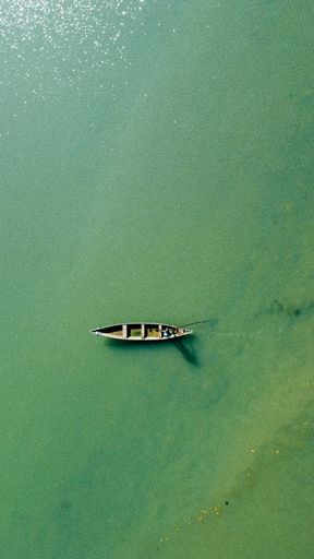 A vertical shot of an aerial shot of a boat on the water on a sunny day