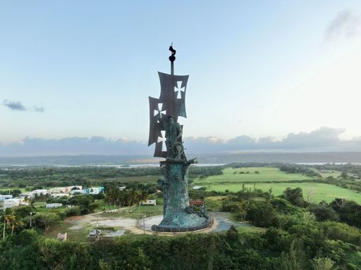 A scenic image of the Statue of Columbus, surrounded by lush green vegetation in Arecibo, Puerto Rico
