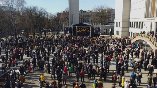 A drone view of the people gathering in front of a stage for an event with flags during the daytime in Kaunas ,Lithuania
