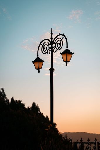 A picturesque landscape featuring a large street light standing tall with trees in the background