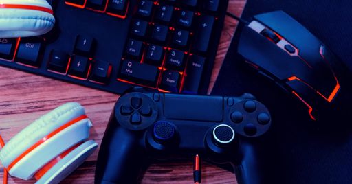A closeup shot of gamer workspace with a keyboard, mouse, headset and a joy
