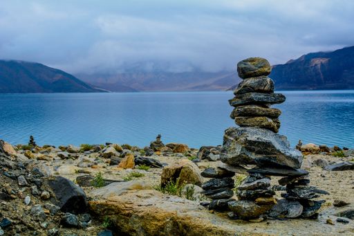 Different sized rocks stacked and balanced one on another at the coast of a beautiful sea in the background