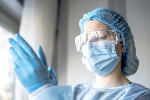 A female doctor putting on protective blue gloves