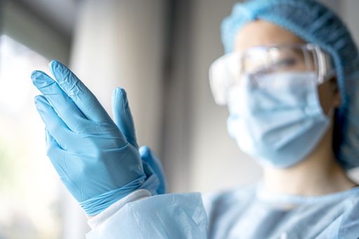 A female doctor putting on protective blue gloves