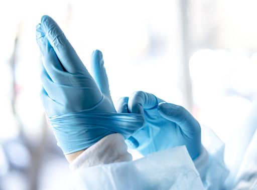 A female doctor putting on protective blue gloves