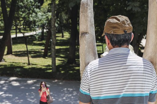 A back view of a middle-aged man having a rest in a park with his wife