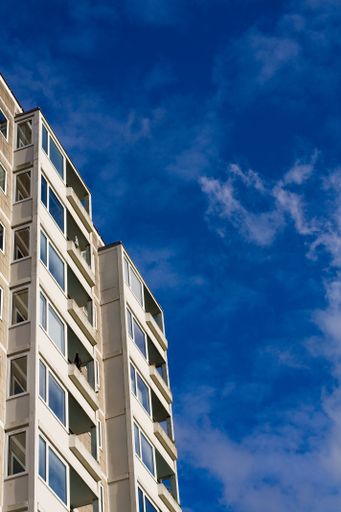A vertical low-angle shot of a residential building before the blue sky on a sunny day