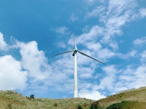 A low angle shot of a windmill on hill under sunlight and blue sky at daytime - environmental concept