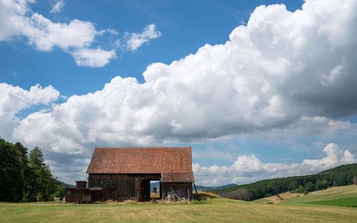 A rustic wooden barn in a grassy field in Sauerland, Germany