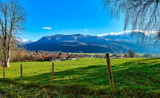The beautiful view of the green field and village against the background of mountains. Bavaria, Germany.
