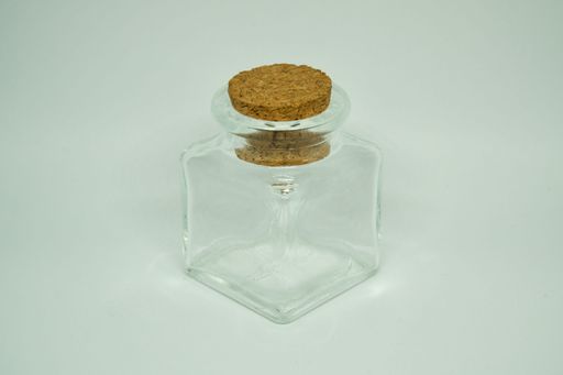 A closeup shot of a small glass jar with a cork lid isolated on a white background