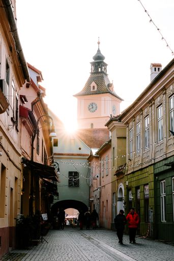 A corridor from the Enescu Square in Brasov, Romania - Sun-star between old town-hall tower and houses