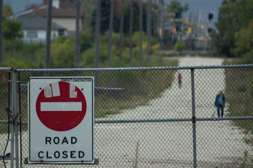 A closeup shot of a "road closed" sign on the fence