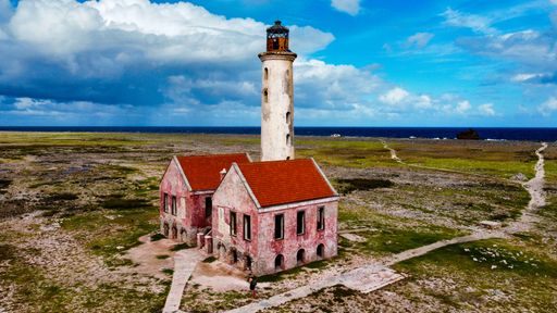An aerial top view of an old abandoned lighthouse under a beautiful cloudscape in Little Curacao uninhabited island