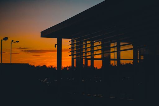 A scenic sunset over a building with parked cars in front of it