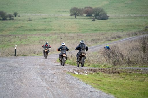 A rear view of a group of cyclists riding their off-road bikes along a stone track