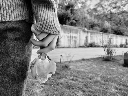 A black and white shot of a rose in a girl's hands