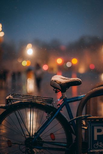 A vertical shot of a bicycle on a snowy night in the city of Nis, Serbia.