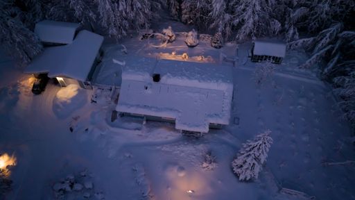 Aerial view around a house with a snow covered solar panel system on the roof, cold winter evening