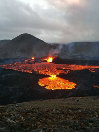 A volcano with lava pouring into the air from a crater