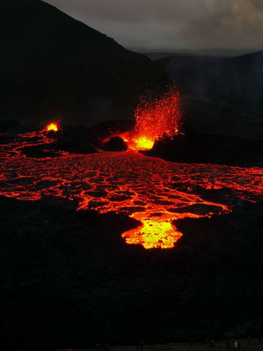 A volcano with lava pouring into the air from a crater