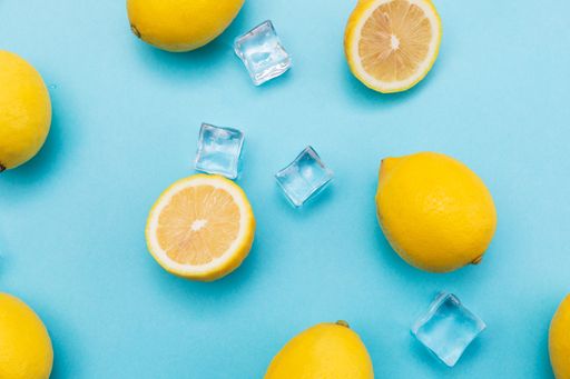 A top view of sliced lemons and ic cubes on baby blue background