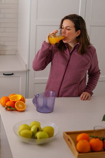 close-up of a young brunette girl in profile drinking freshly squeezed orange juice