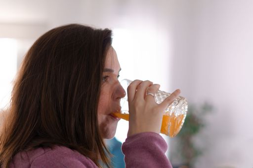 close-up of a young brunette girl in profile drinking freshly squeezed orange juice