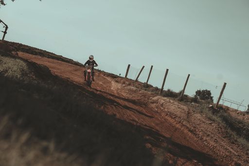 A crazy motor cyclist (biker) in dirt riding their off-road motorbike