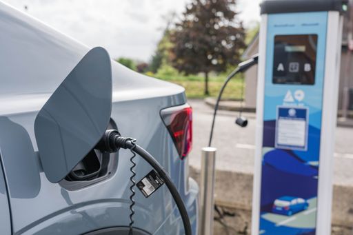 An electric car being charged with a charger connected to the road