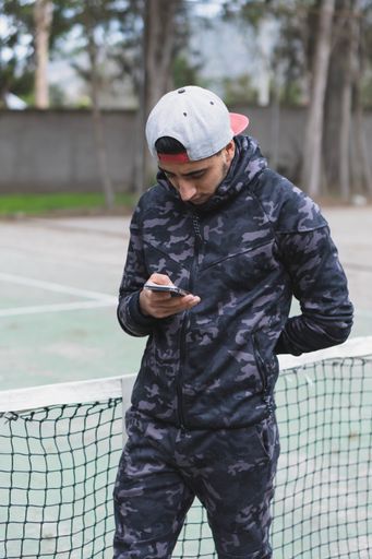 A young sportsman looking at his phone and getting ready to do a workout in the park