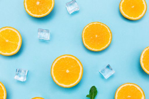 A top view of sliced oranges and ice cubes on baby blue background