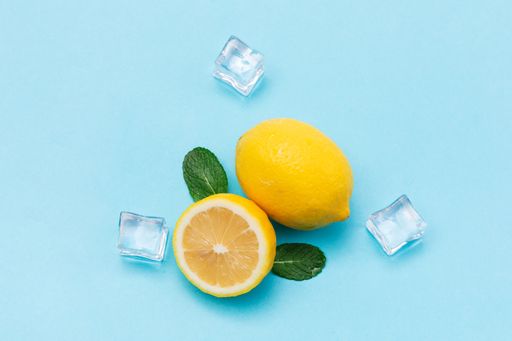 A top view of lemons and ice cubes on baby blue balcground