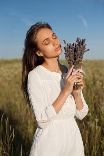 Portrait of a gorgeous young woman holding lavenders outdoors.