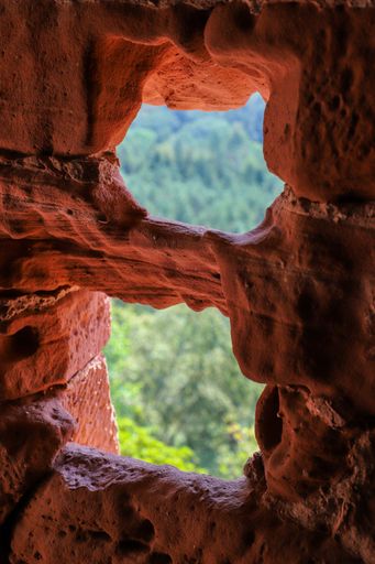 A vertical composition of a cave wall featuring two natural holes, illuminated by natural light