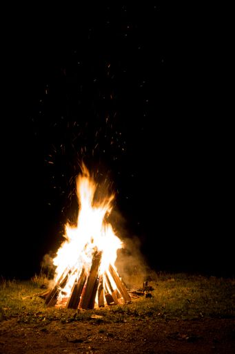 A vertical shot of a large burning bonfire in the night