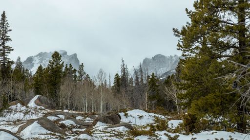 A landscape of Snow covered mountains in Estes Park, Colorado in winter with trees in the foreground