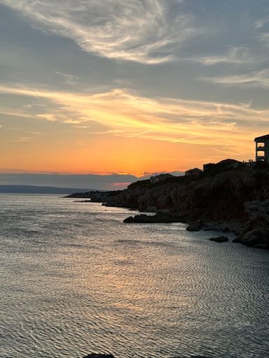 A rocky cliff coast line by the sea under sunset sky, vertical shot