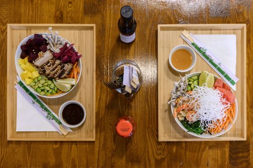 A closeup top view shot of two portions of Asian dishes with various ingredients and chopsticks