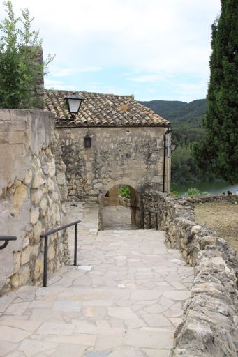 A vertical shot of a tiled walkway leading to an arched passage of an old stone-made building