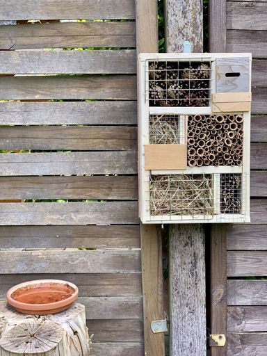 A vertical shot of a hotel for insects hanging from a garden wooden wall