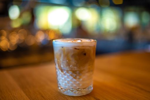 An Iced latte Coffee in a Crystal Glass a Wooden Bar Table