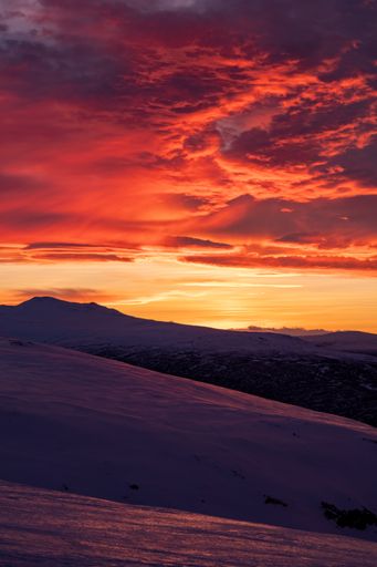 A vertical shot of a beautiful colorful sunset on a mountainside