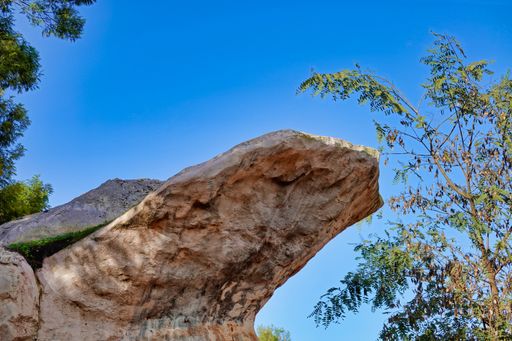 A low angle shot of a large stone formation under a blue sky