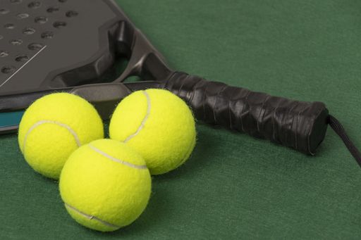 A padel tennis racket and balls in the green background