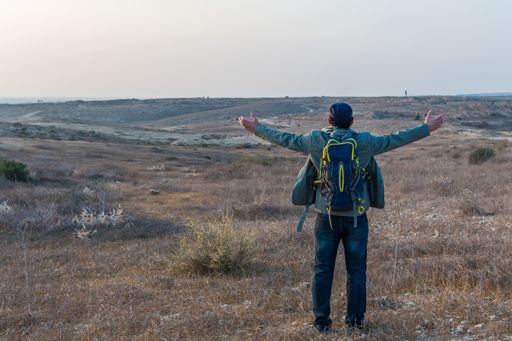 An adventurer stands with open arms, enjoying the landscape at sunset, in winter.