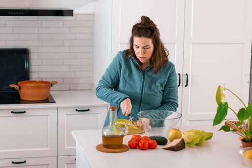 young brunette girl chopping lettuce to prepare a salad in the kitchen